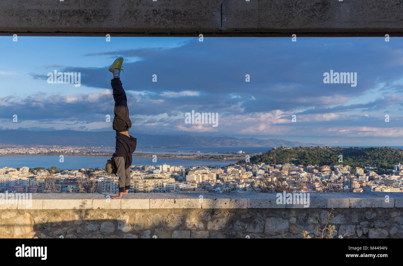 L'uomo facendo handstand sulla parete, Cagliari, Sardegna, Italia Foto Stock