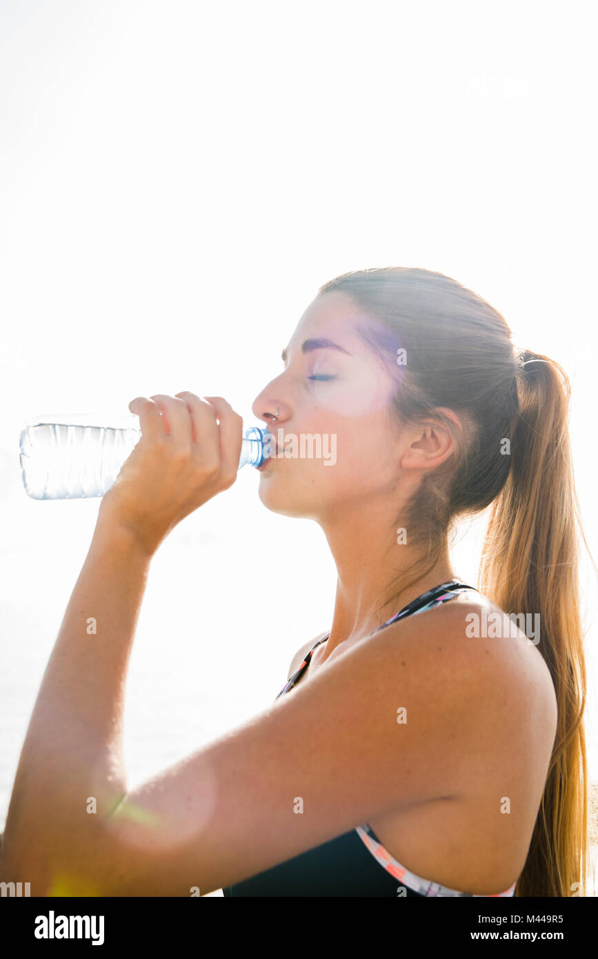 Giovane donna formazione, bere acqua in bottiglia Foto Stock