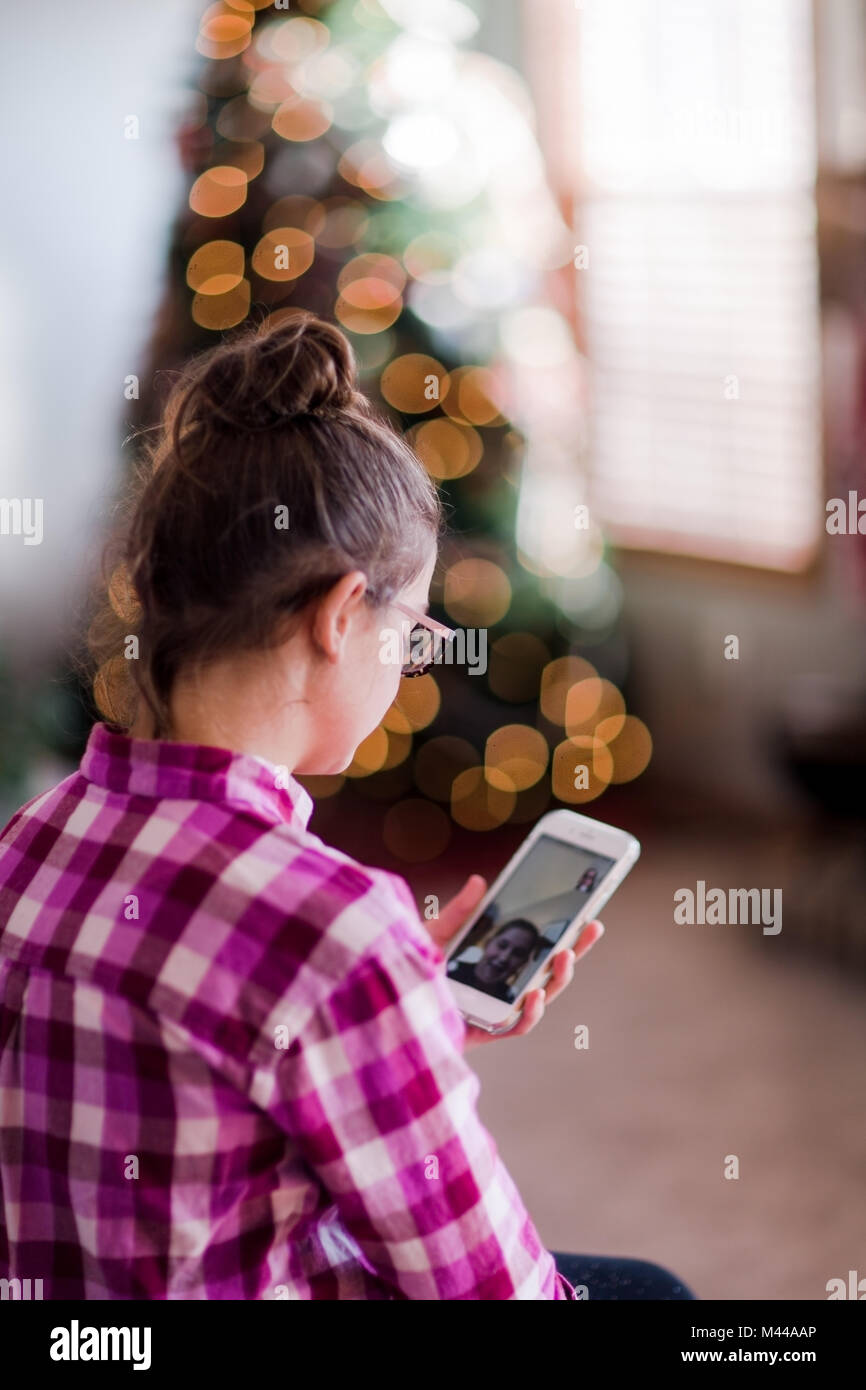 Ragazza a casa, avente la chiamata video con un amico, utilizza lo smartphone Foto Stock
