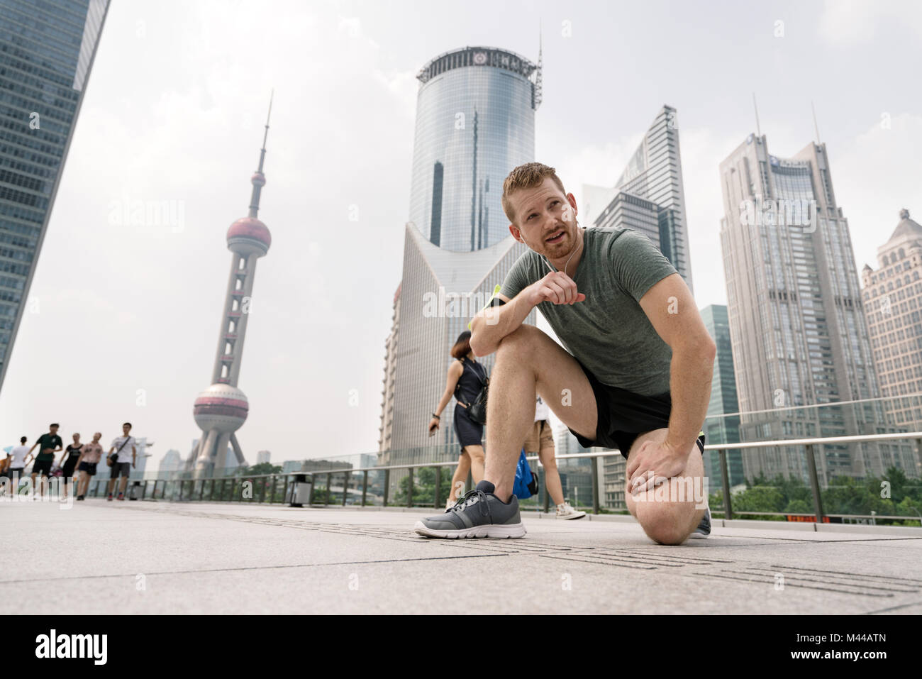 Giovane maschio runner prendendo una pausa a Shanghai centro finanziario di Shanghai, Cina Foto Stock