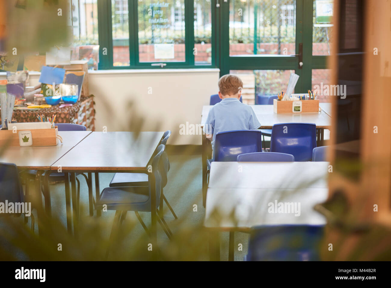 Scolaro seduto alla scrivania in aula presso la scuola primaria, vista posteriore Foto Stock