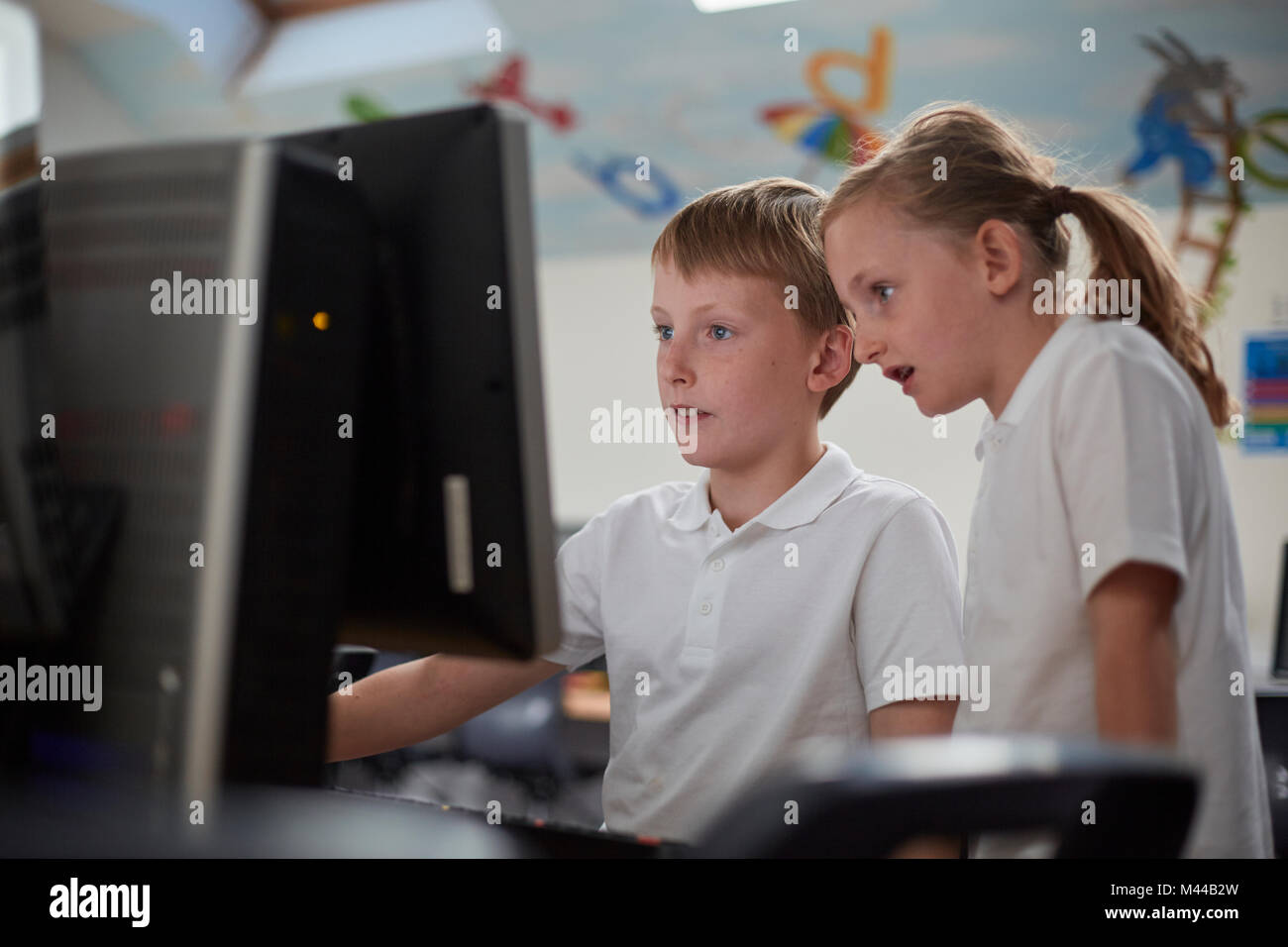 Scolaro e ragazza utilizzando il computer in aula presso la scuola primaria Foto Stock