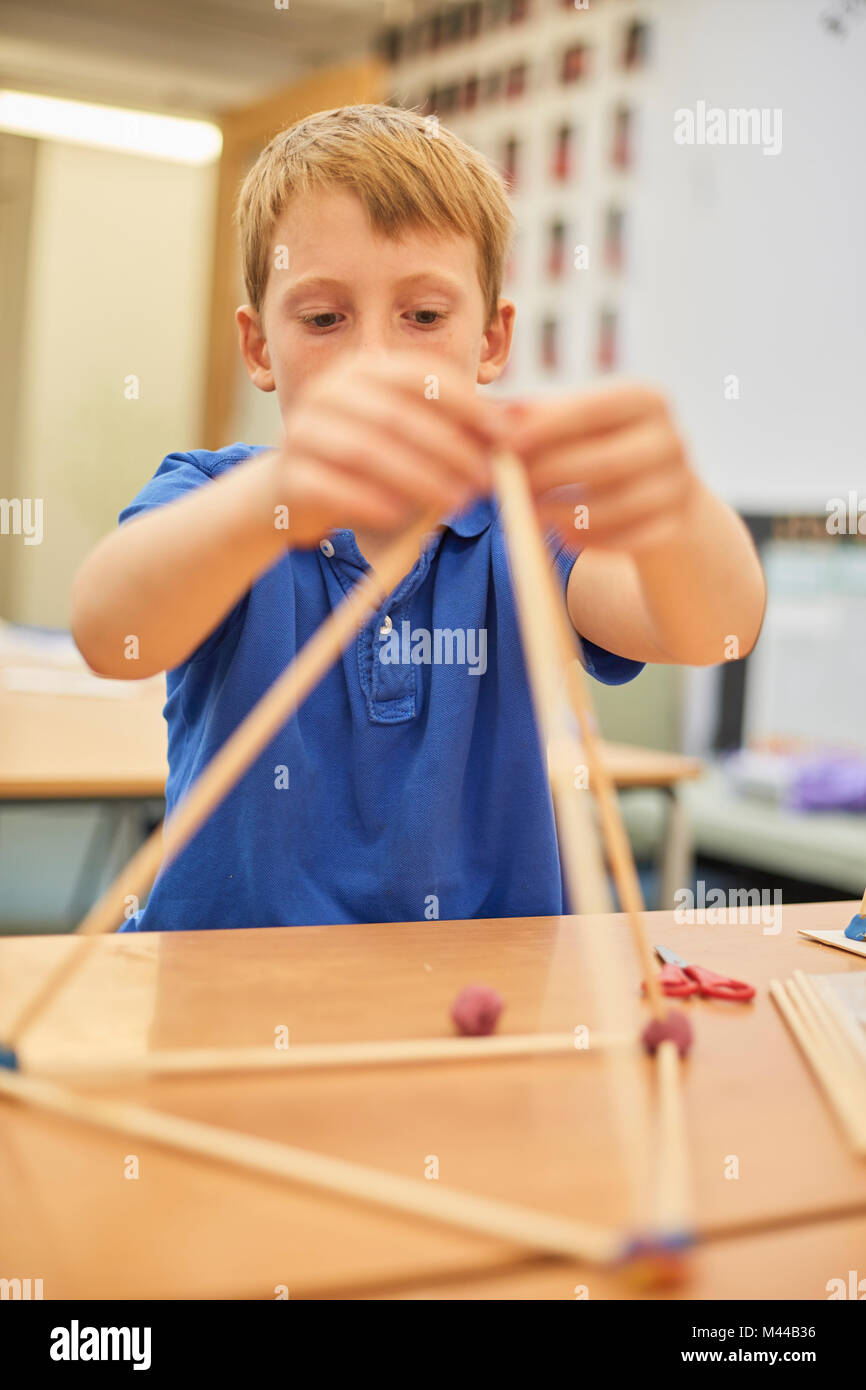 Scolaro rendendo la sfera e stick modello in aula presso la scuola primaria Foto Stock