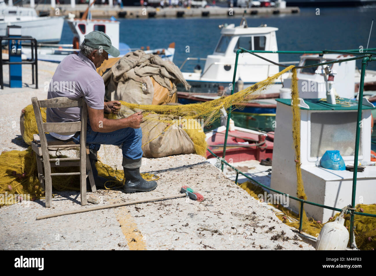 Fisherman riparazione di reti da pesca sul Quayside, Kamares, SIFNOS, CICLADI, il Mare Egeo e le isole greche, Grecia, Europa Foto Stock