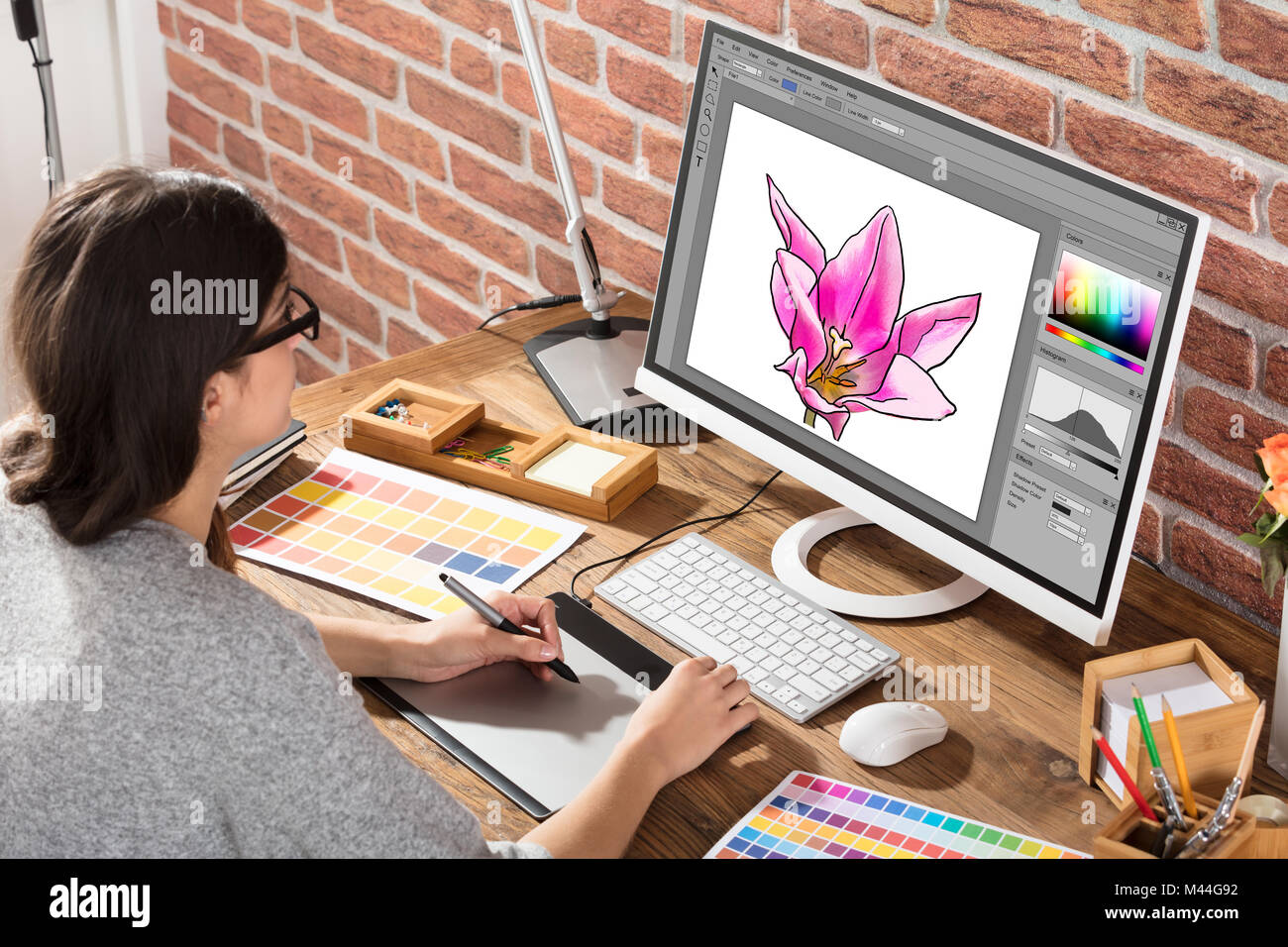 Angolo di alta vista del designer femmina disegno fiore sul computer utilizzando tavoletta grafica in ufficio Foto Stock