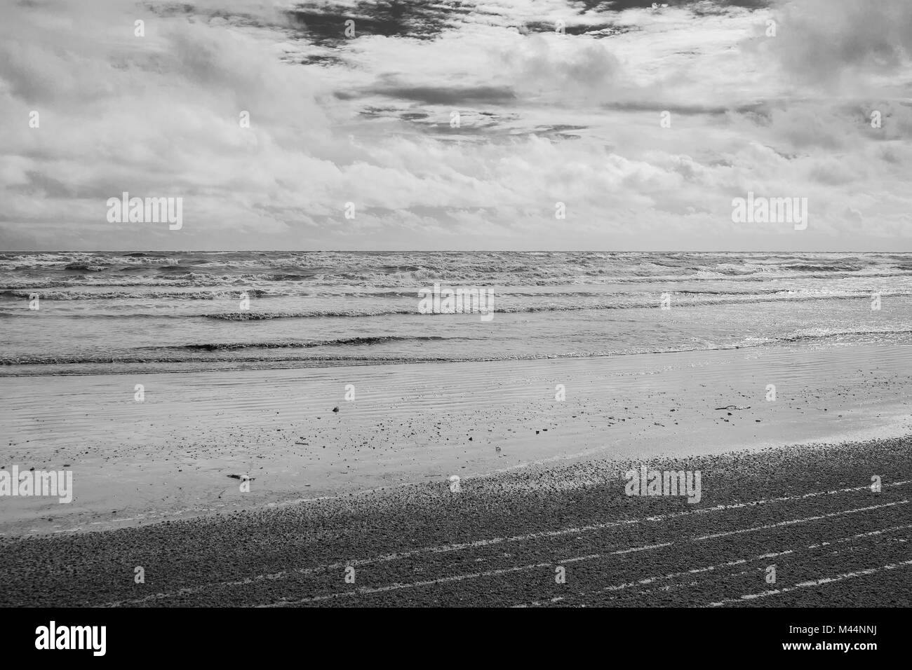 Immagine in bianco e nero seascape vista della spiaggia di sabbia e mare sullo sfondo di onda in giorno di pioggia. Foto Stock