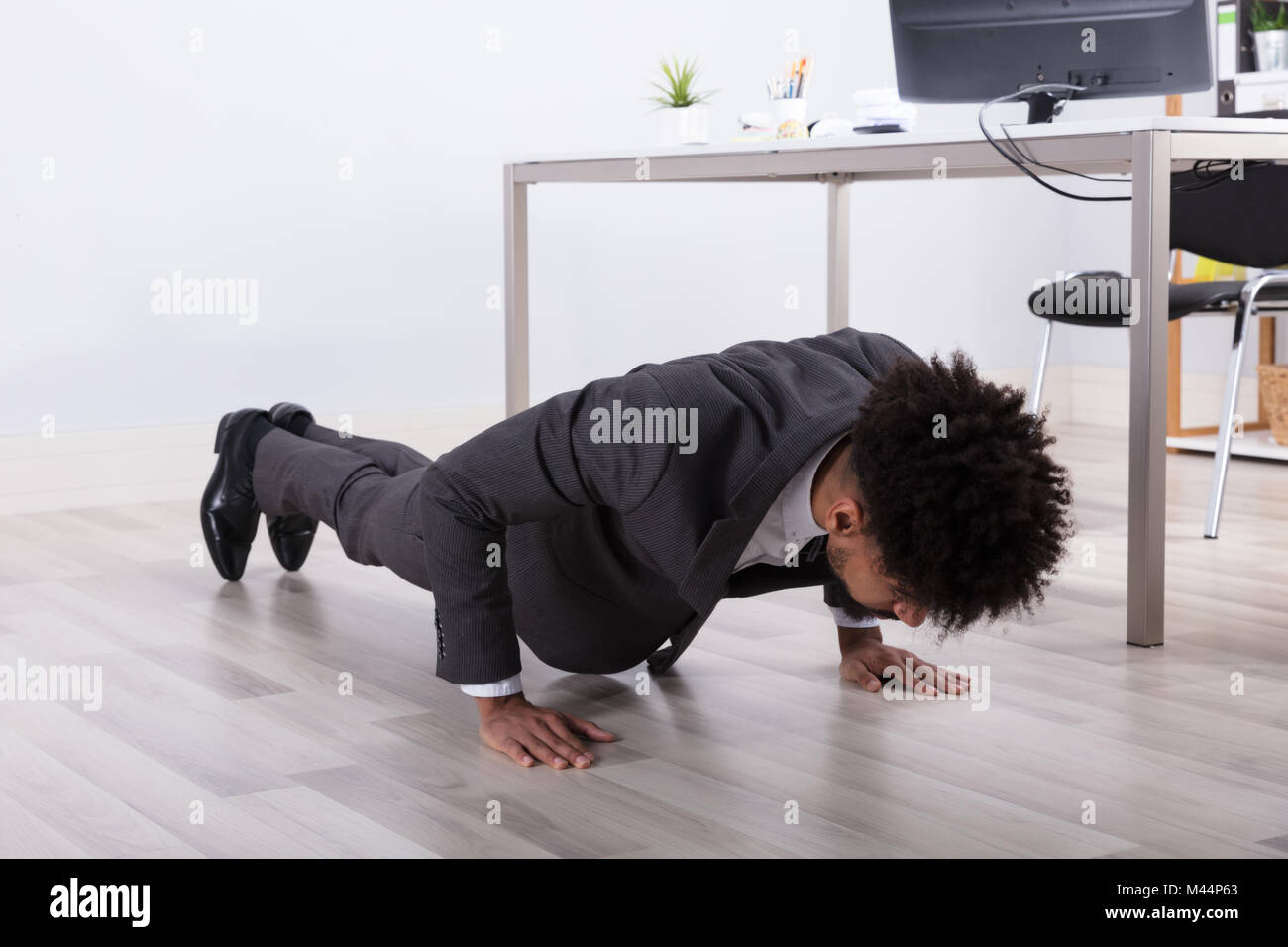 Giovane Imprenditore facendo spingere in alto sul pavimento nel luogo di lavoro Foto Stock