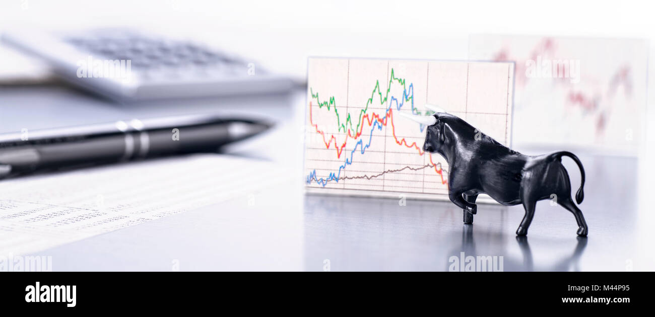 Scrivania con la figura di un toro e un grafico con il prezzo sul mercato azionario Foto Stock