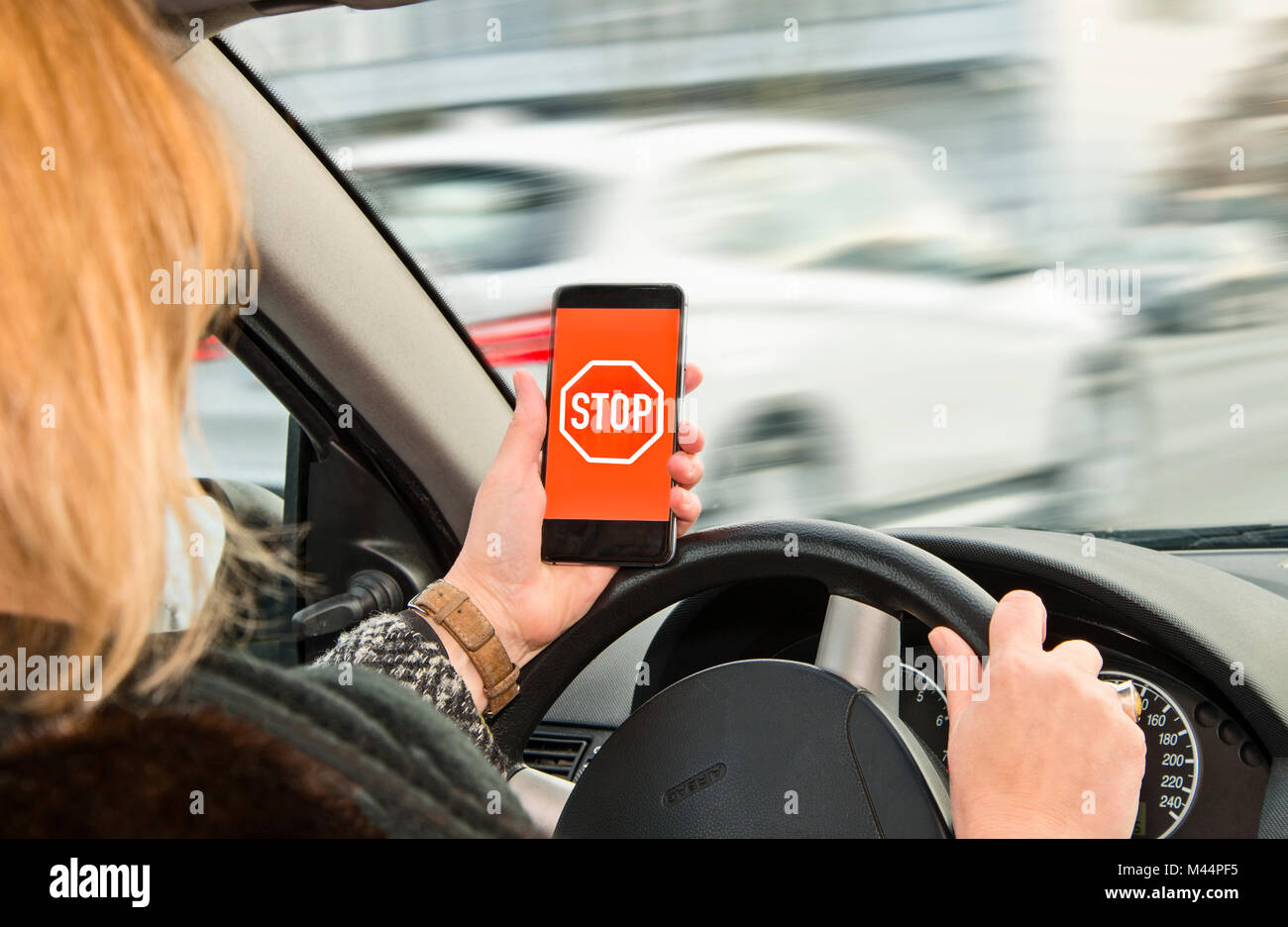 La donna possiede uno smartphone con segno di stop in sua mano durante la guida Foto Stock