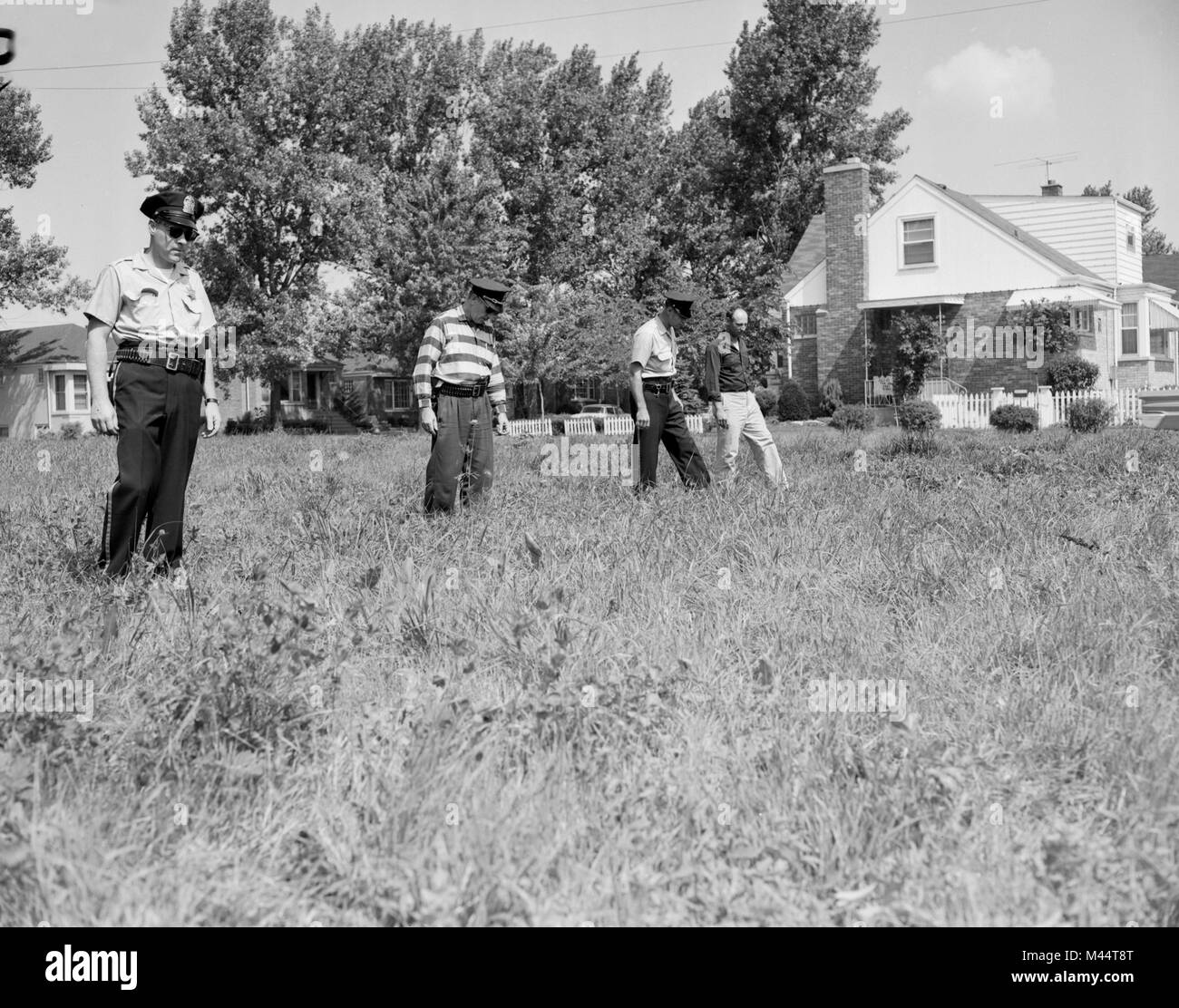 La polizia cerca un campo di indizi di un crimine, ca. 1960. Foto Stock
