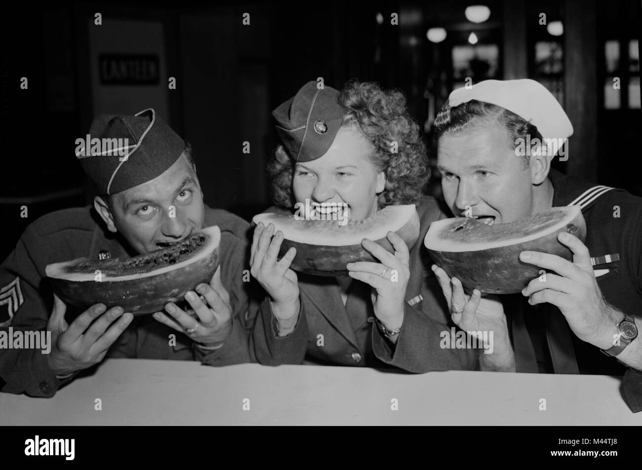 Tre degli stati uniti i membri del servizio chow giù su alcune cocomero, ca. 1945. Foto Stock