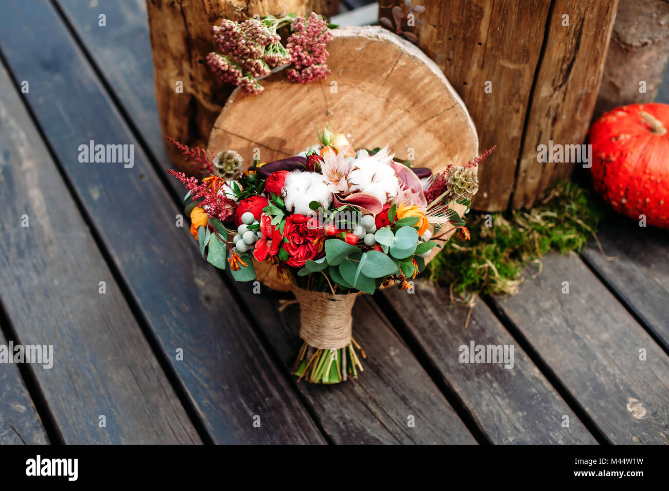 Bouquet nozze con cotone e peonia in stile rustico con pavimento in legno. Ceppi di legno e zucche sullo sfondo Foto Stock