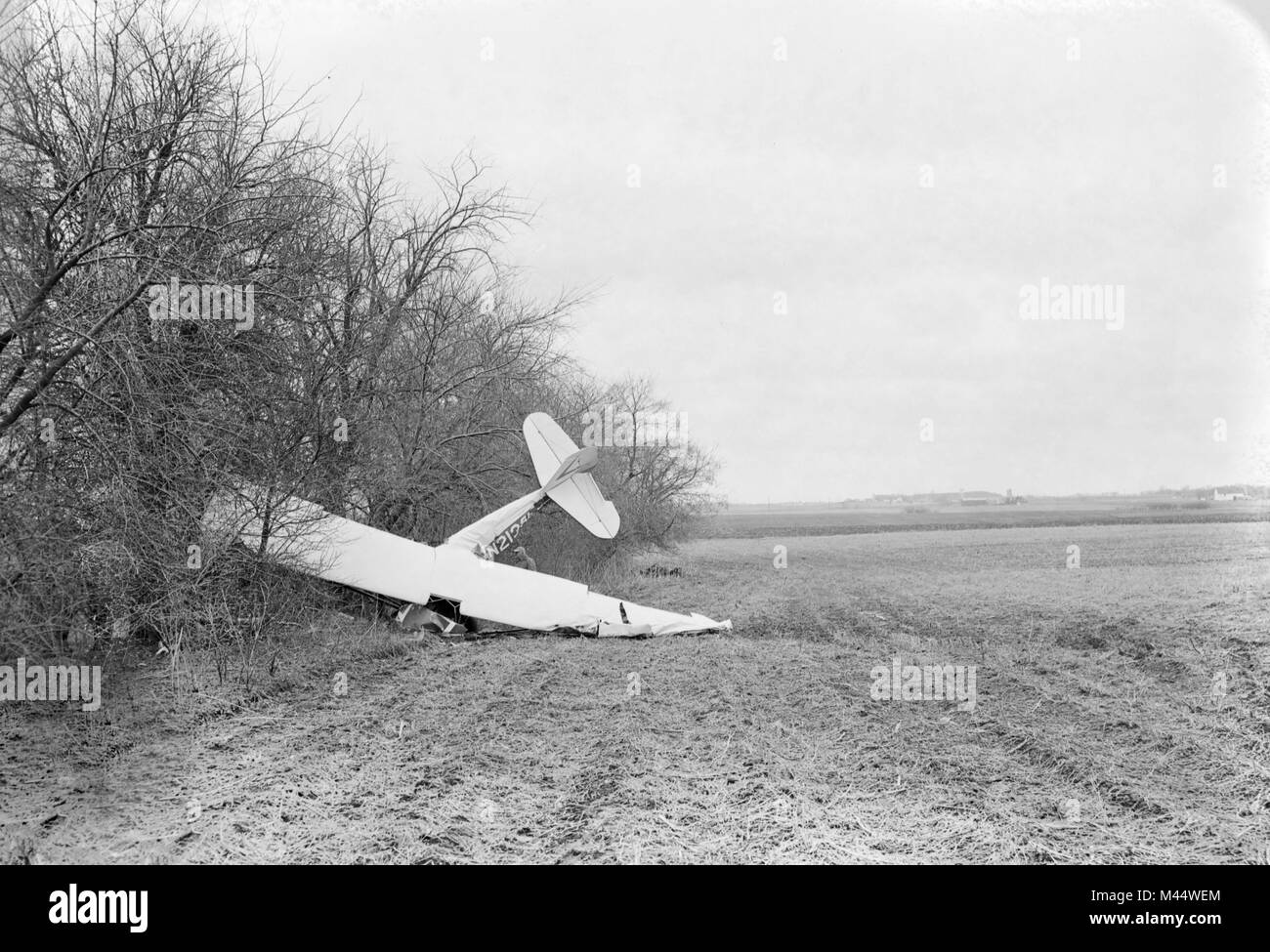 Un unico motore di aeroplano è accoccolato contro un albero linea dopo un crash in un'Illinois campo di fattoria, ca. Foto Stock