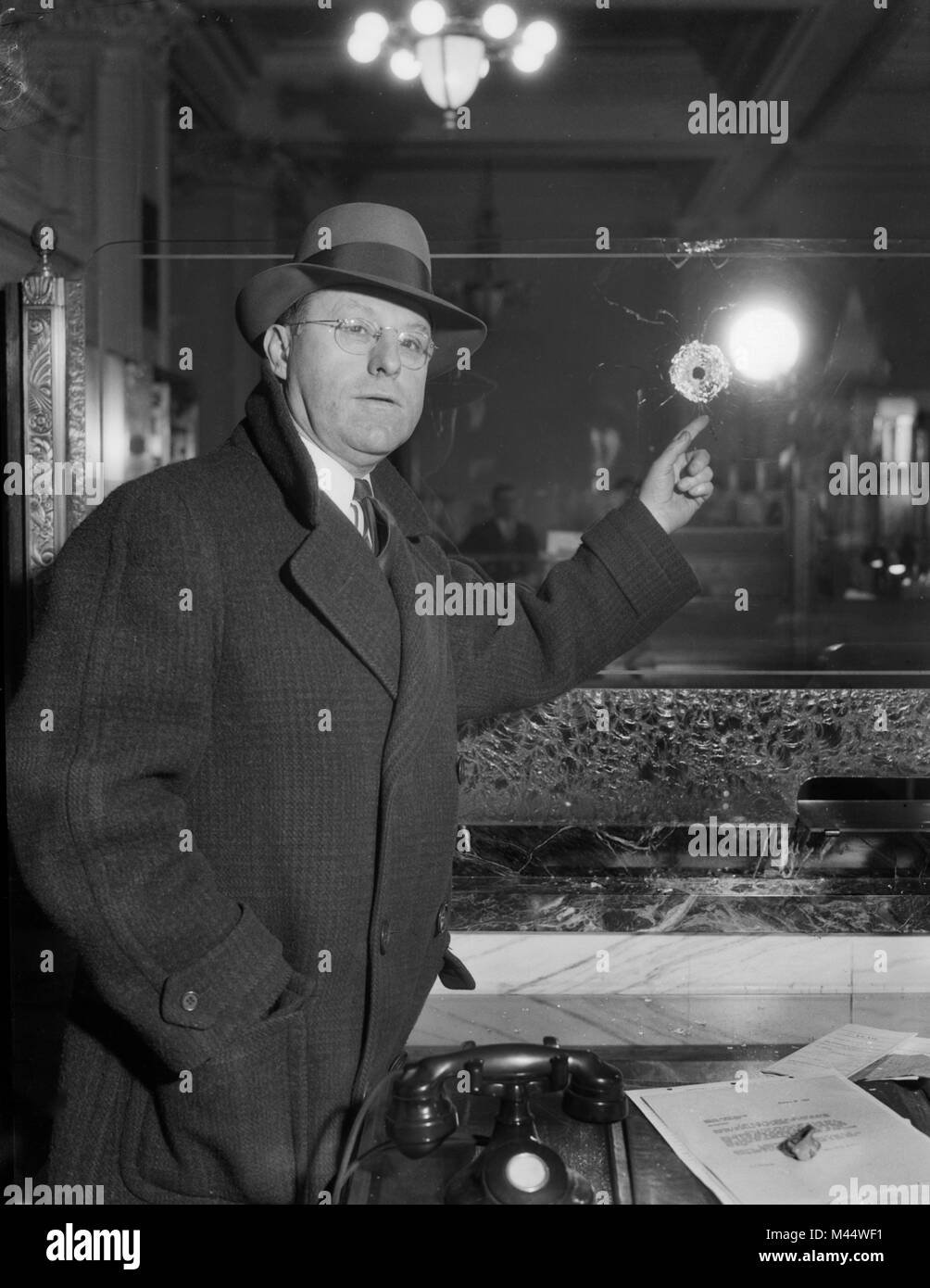Un ispettore di polizia ricorda un foro di proiettile in una banca di Chicago dopo una rapina, ca. 1930. Foto Stock