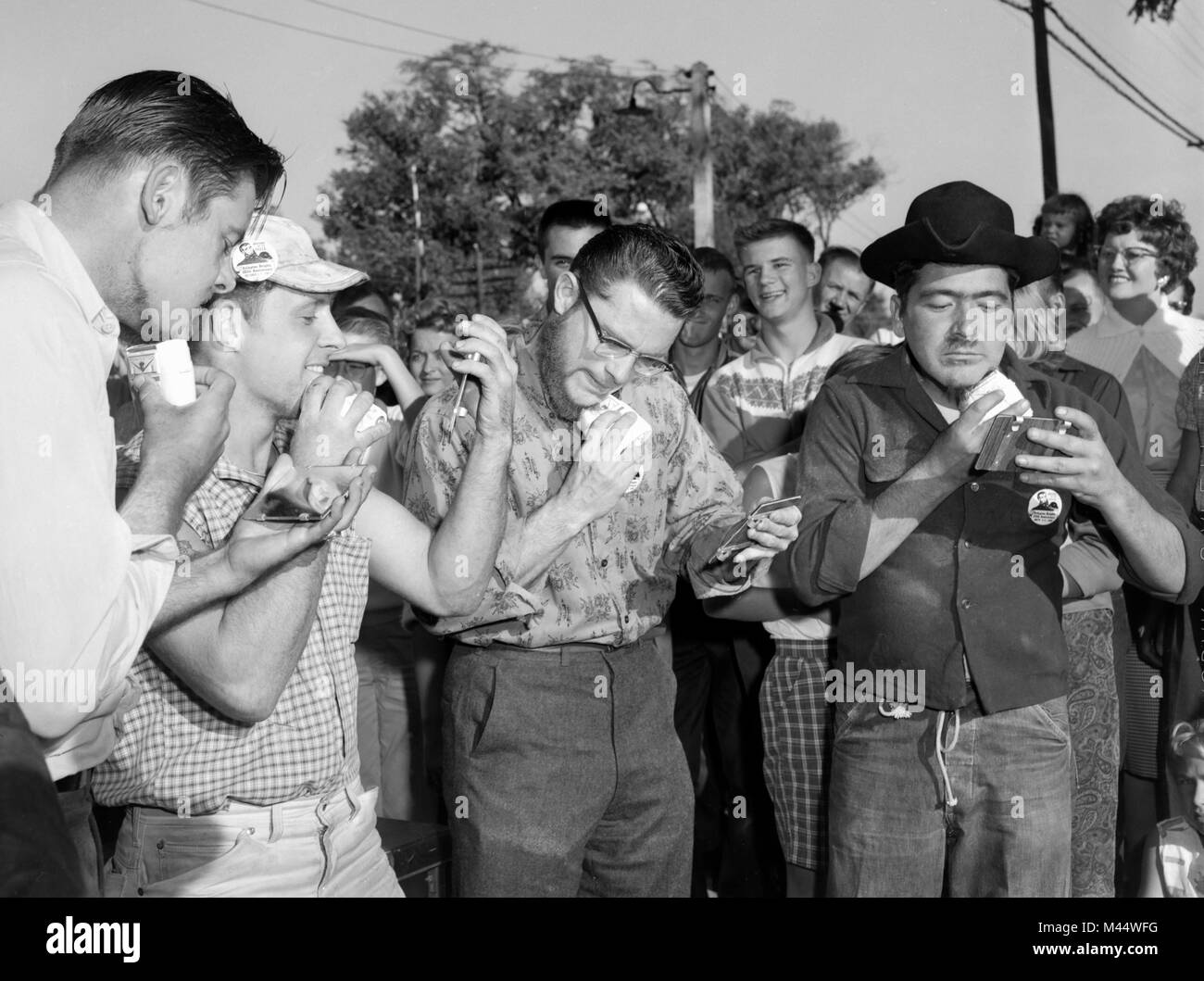 Gli uomini utilizzano la nuova tecnologia di alimentato a batteria rasoi elettrici in un concorso di rasatura in Illinois, ca. 1964. Foto Stock