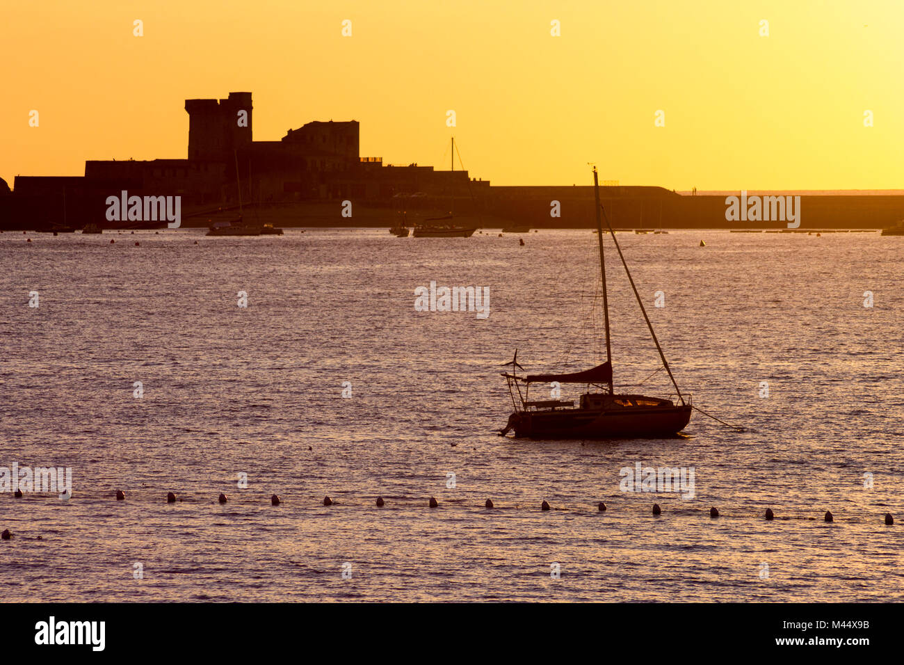 Vista al tramonto del Fort de Socoa a Saint-Jean-de-Luz, Francia, con una barca retroilluminato in primo piano Foto Stock