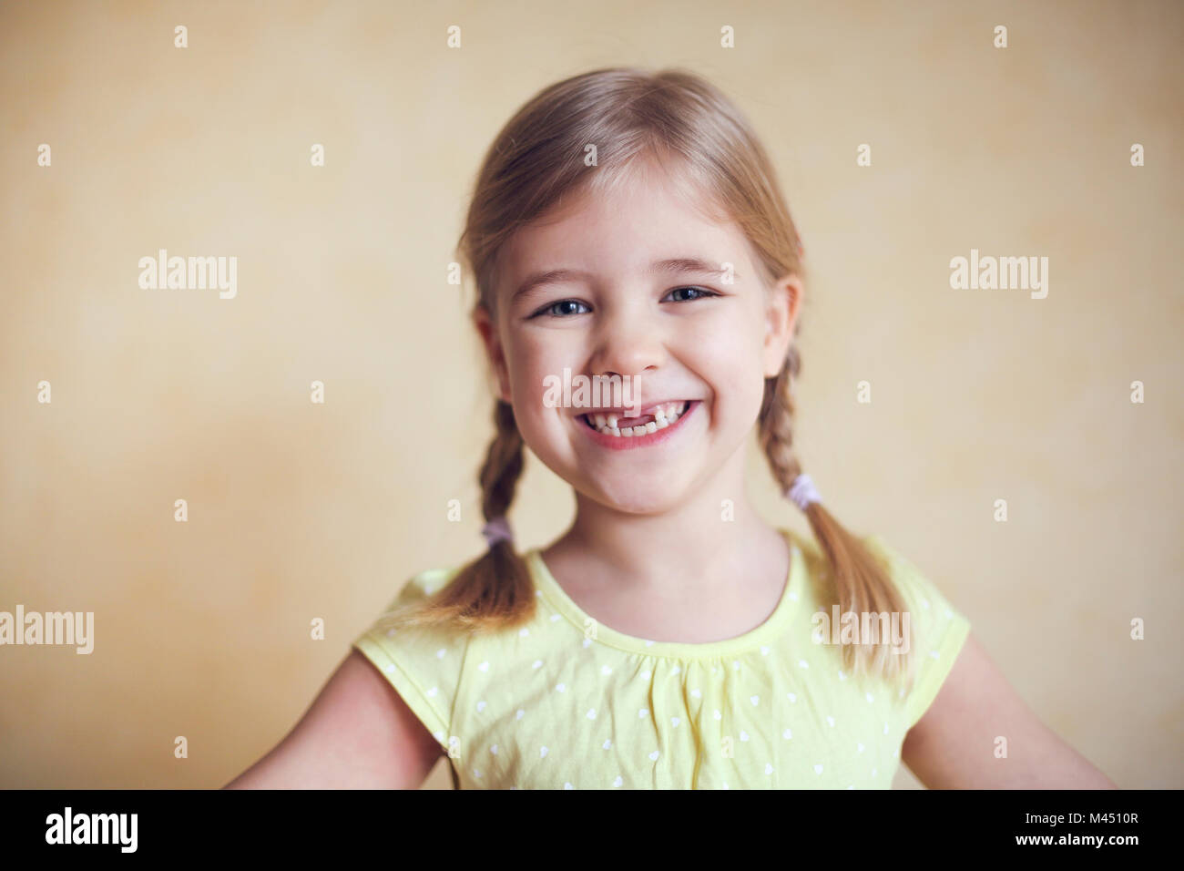 Felice dente perduto bambina ritratto, studio spara su sfondo giallo Foto Stock