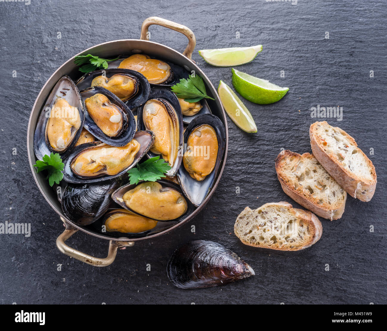 Bollito di cozze in padella di rame su sfondo di grafite. Foto Stock