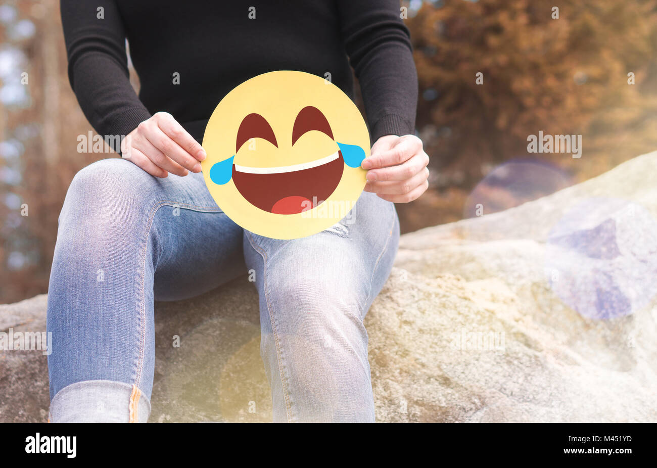 Ridendo emoticon con lacrime di gioia. Donna con divertimento fuori e tenendo un allegro carta stampata Smiley face. Comunicazione felice e sorridente icona. Foto Stock