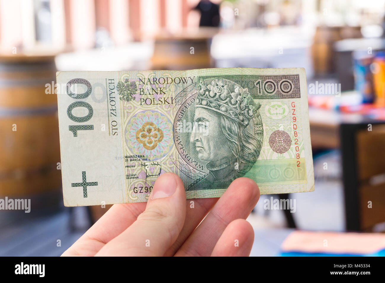 Uomo con 100 zloty polacco bill nel ristorante sulla terrazza all'aperto. Turista che mostra un centinaio di banconota. Foto Stock