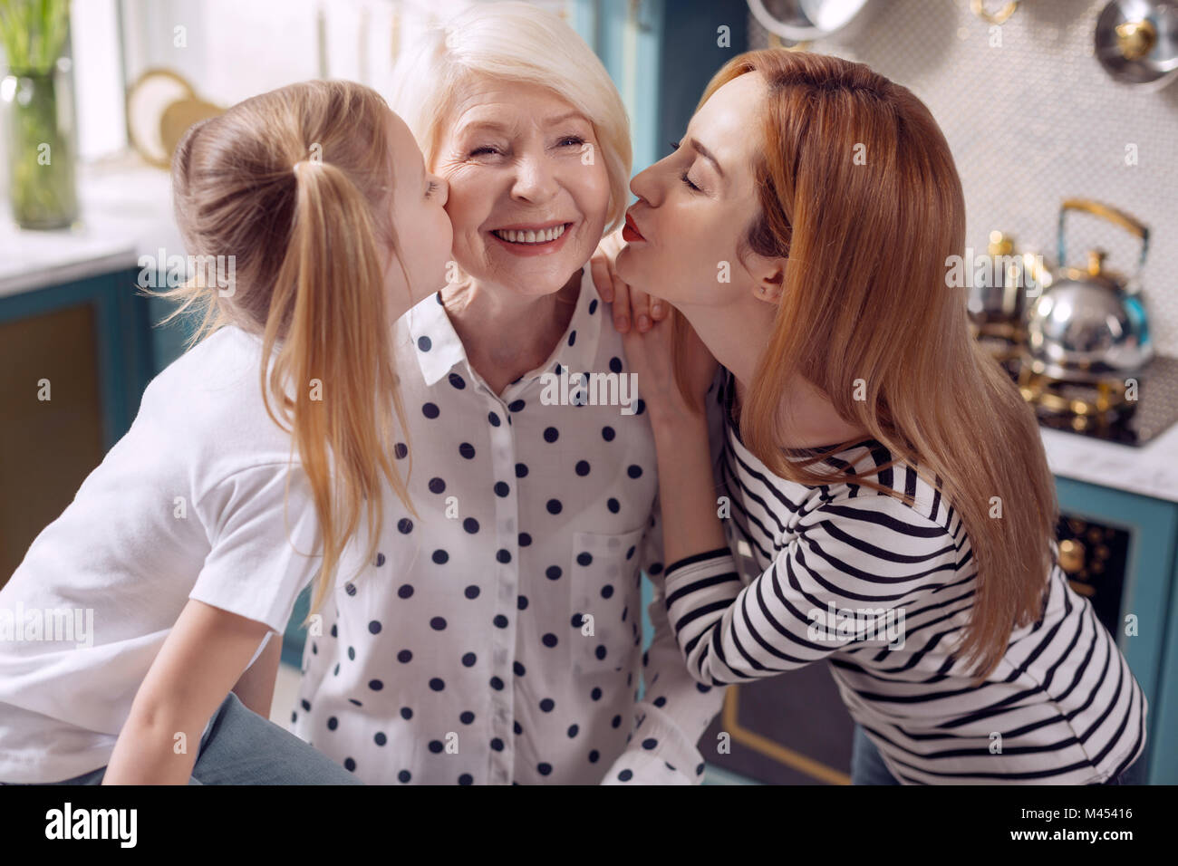 Bambina e sua madre baciare la nonna sulle guance Foto Stock