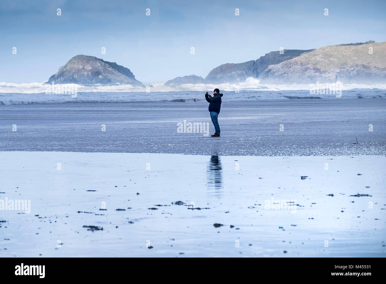 Un uomo che utilizzano uno smartphone per fotografare Perranporth Beach in Cornwall Regno Unito. Foto Stock