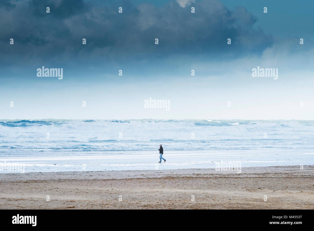 Un uomo che cammina in Perranporth Beach in Cornwall Regno Unito. Foto Stock