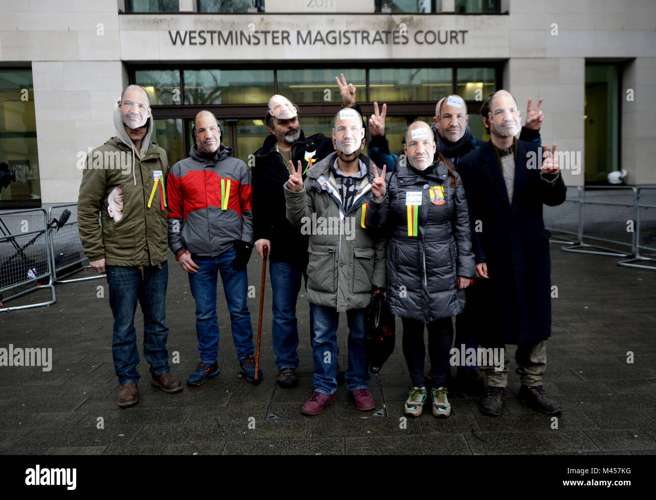 I sostenitori di James Matthews, che hanno combattuto con la milizia curda contro uno Stato islamico, indossare le maschere con il suo volto su fuori di Westminster Magistrates' Court, Londra, dove è comparso caricato con un reato di terrore. Foto Stock