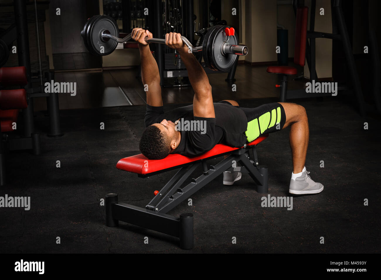Giovane uomo facendo banco armi french press allenamento in palestra Foto Stock