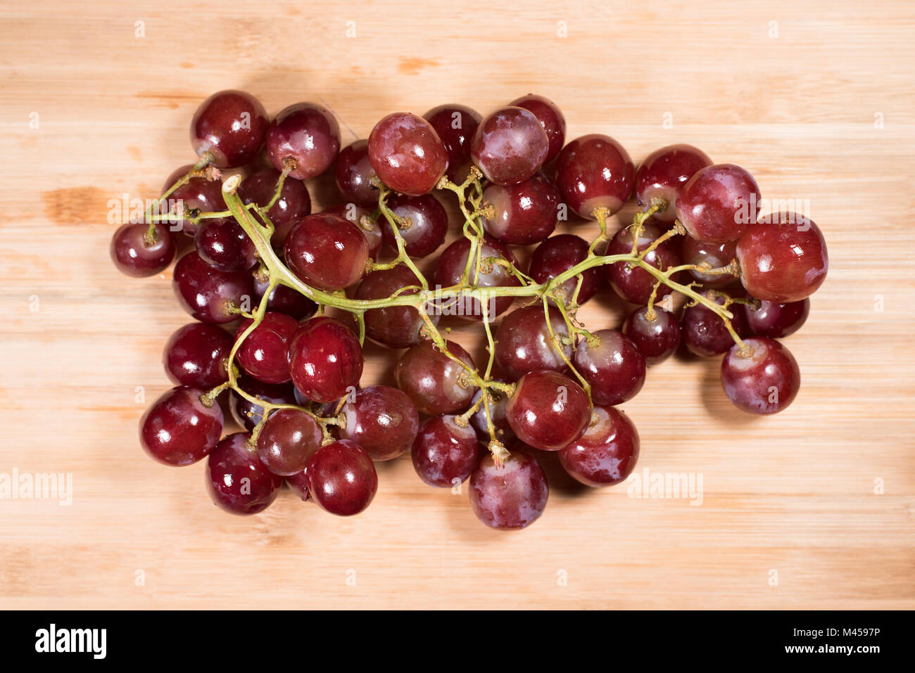 Le uve rosse con piccioli sulla tavola di legno sfondo. rosso uve fresche Foto Stock