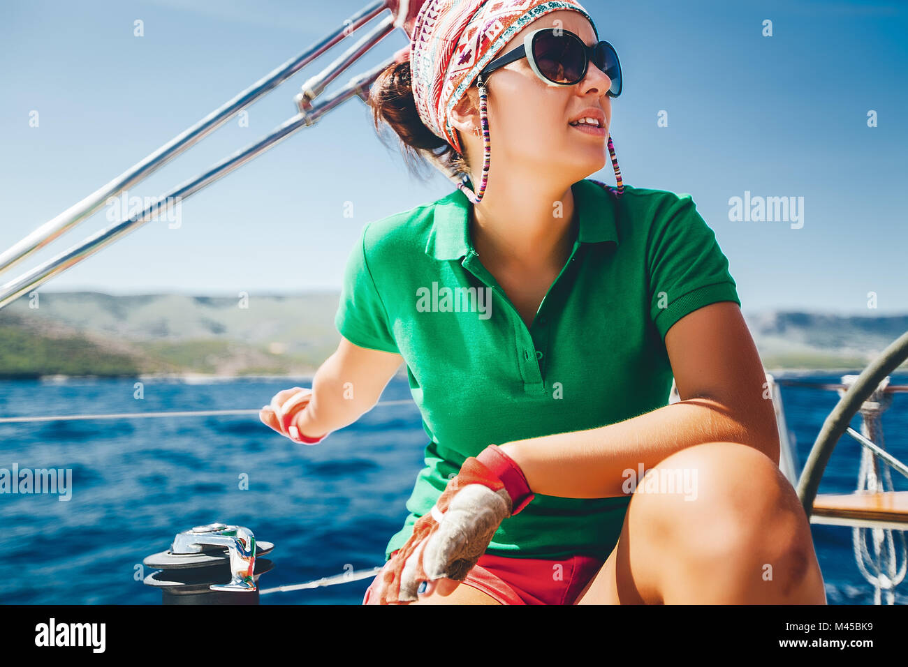 Giovane donna accovacciata su yacht vicino alla costa, Croazia Foto Stock