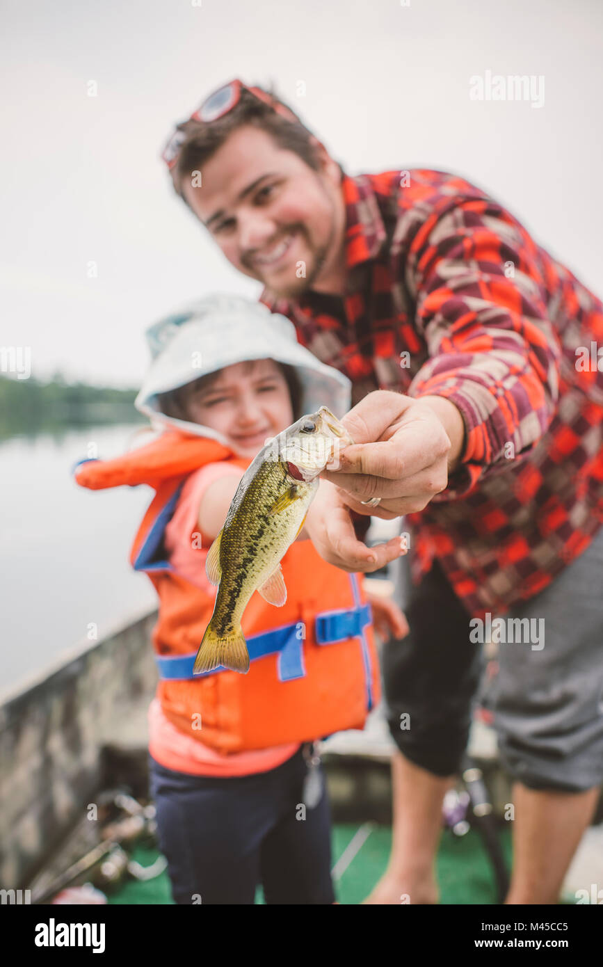 Padre e figlia in barca sul lago, padre che mostra la figlia pesce pescato Foto Stock