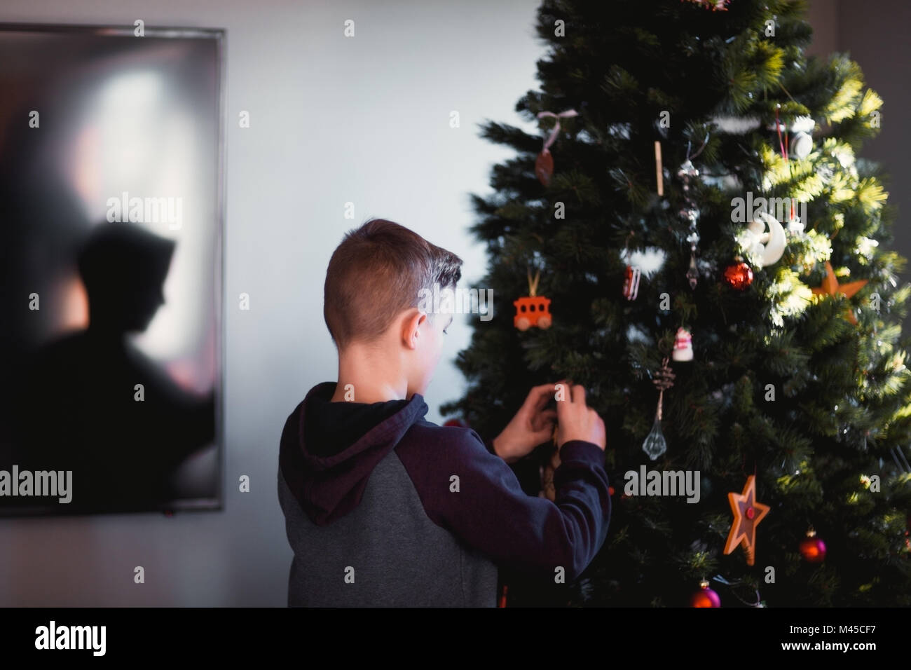 Ragazzo mettendo le decorazioni di Natale Foto Stock