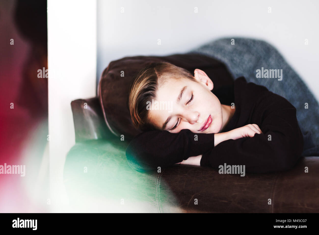 Ragazzo che dorme sul divano in pelle Foto Stock