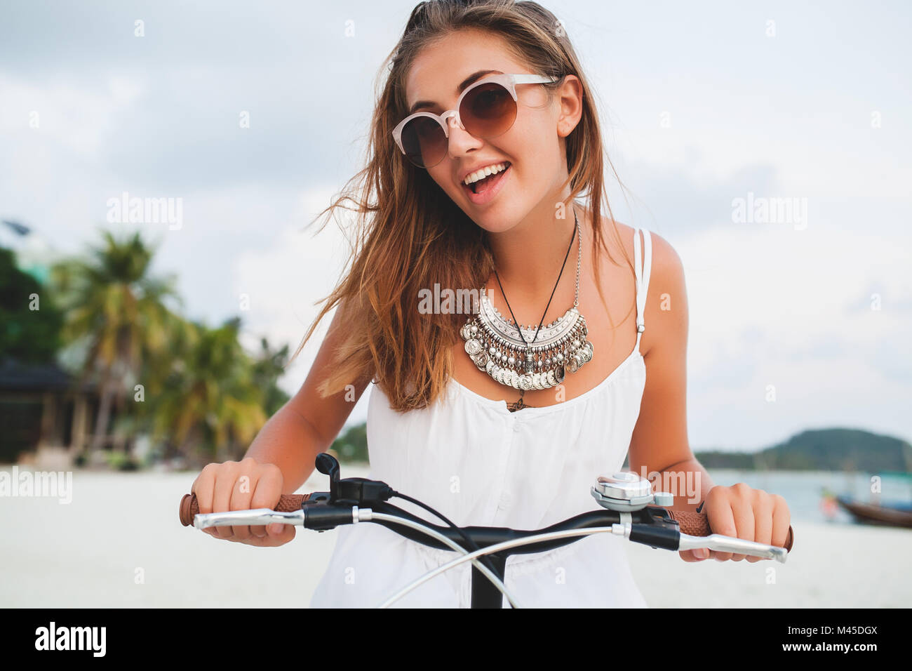 Ritratto di giovane donna tenendo i manubri delle biciclette sulla spiaggia sabbiosa, Krabi, Thailandia Foto Stock
