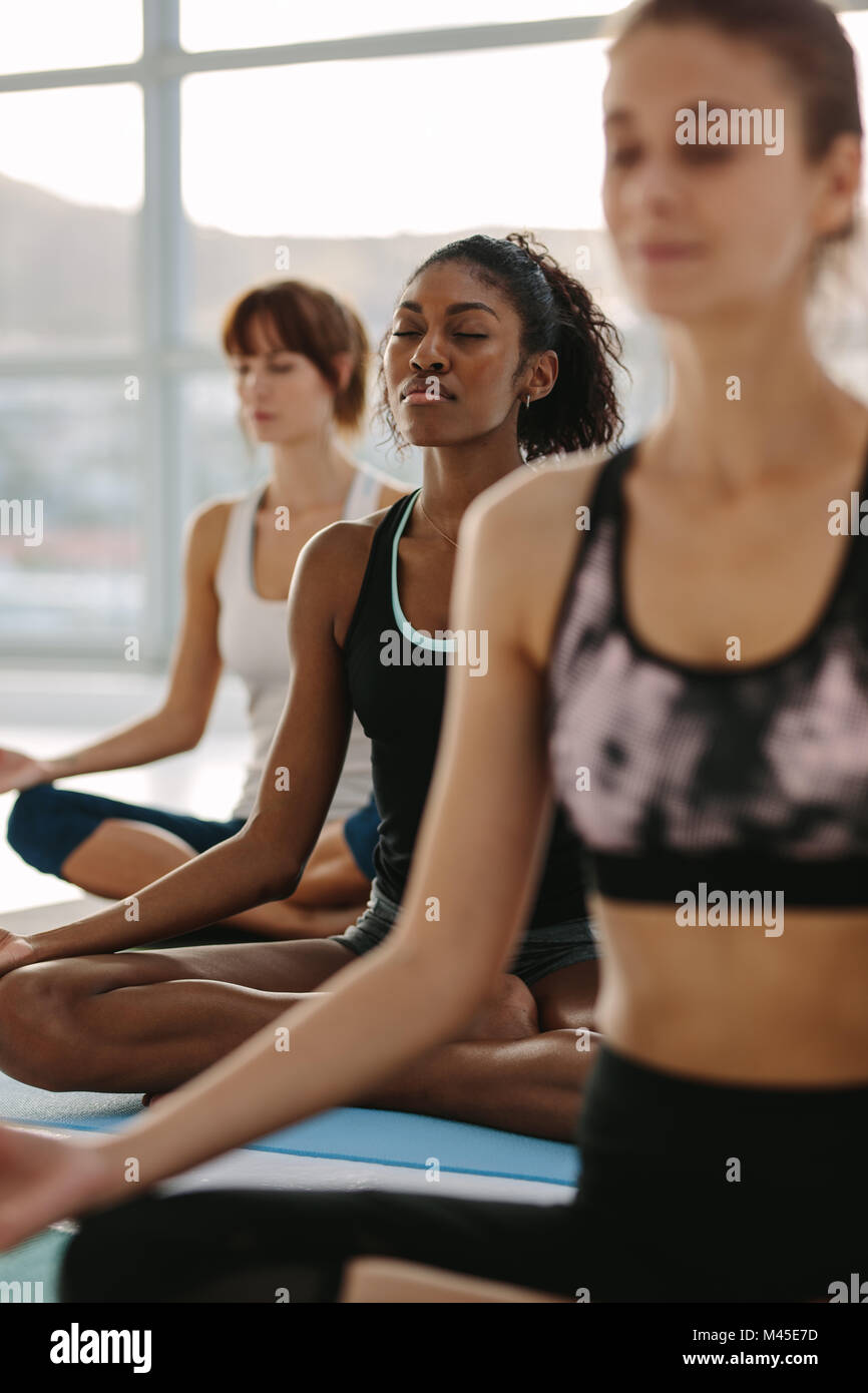 Persone Fitness pratica di mindfulness e tranquilla meditazione yoga allenamento. Il gruppo di donne meditando in lotus posa al fitness studio. Foto Stock