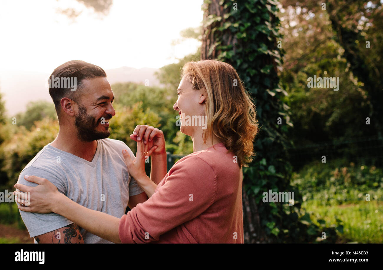 Uomo sorridente con la sua fidanzata in un giardino. Coppia romantica di trascorrere del tempo insieme in un parco. Foto Stock