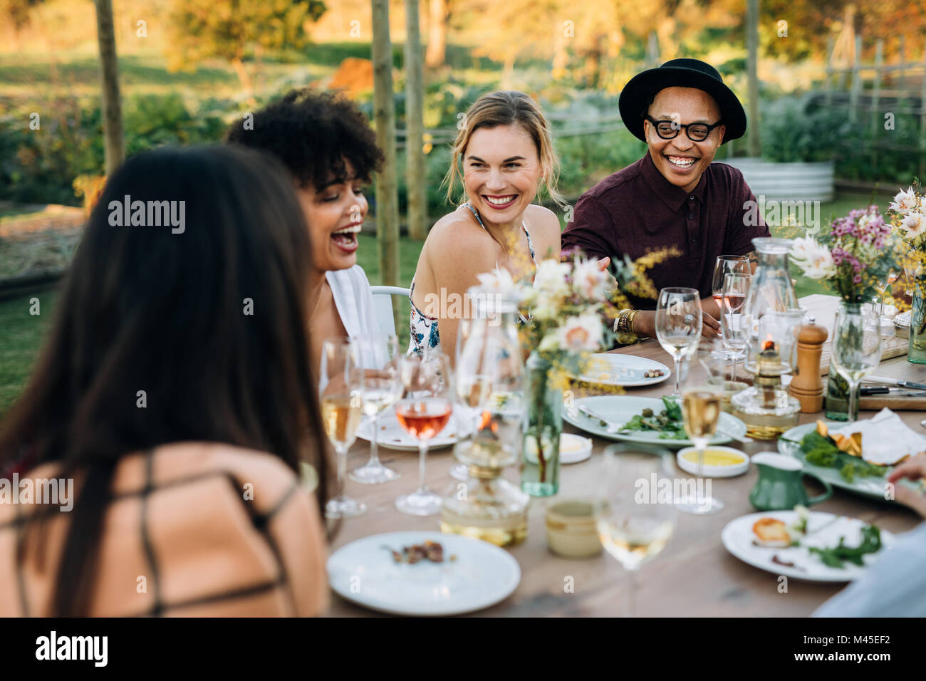 Gruppo di amici gustando party all'aperto nel giardino di casa. Millennial godendo estate pasto presso il ristorante. Foto Stock