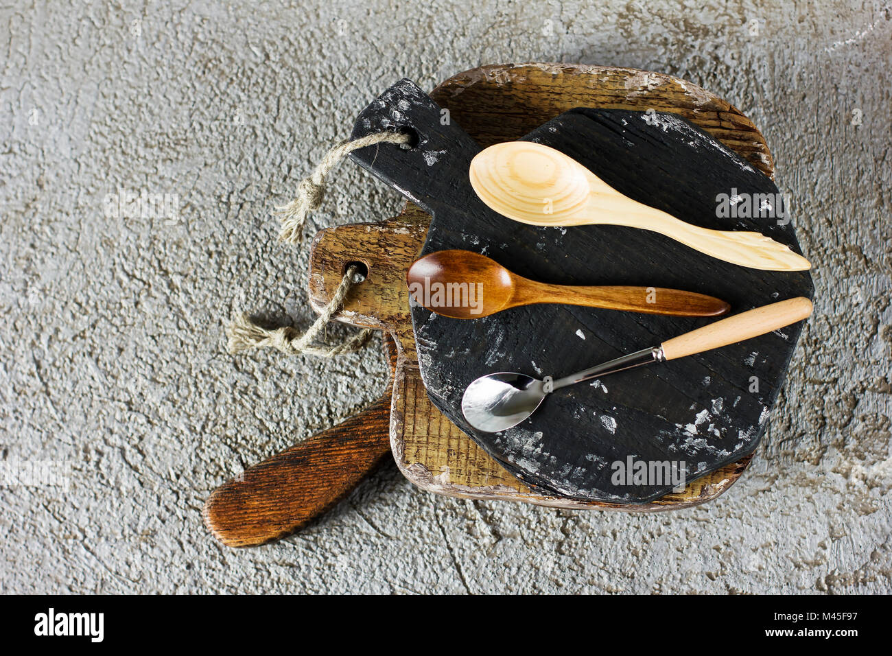 Tavole di legno, ciotola e cucchiai sul cemento grigio Sfondo. Puntelli per la fotografia di cibo Foto Stock