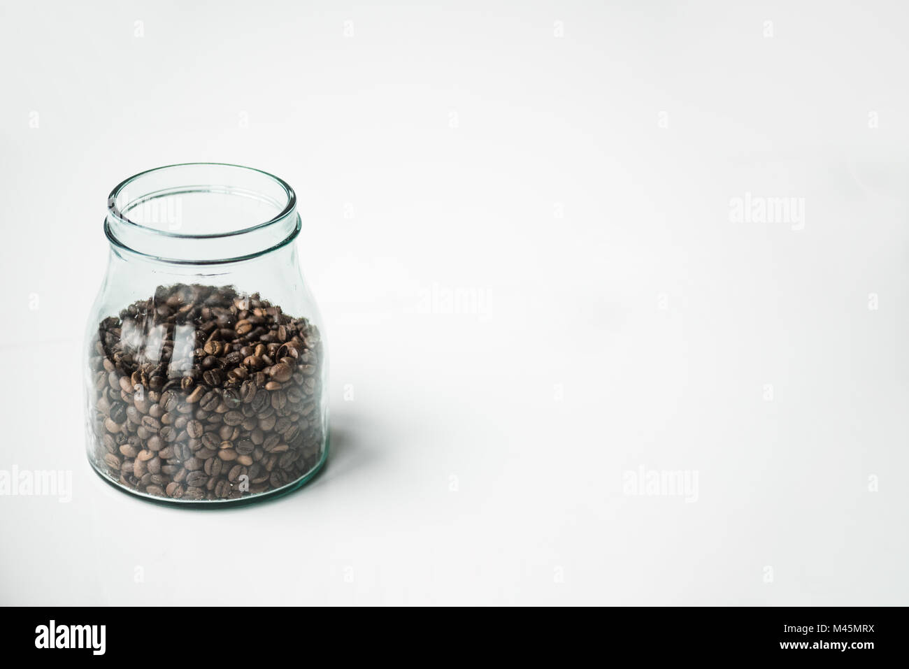 Bottiglia di vetro con i chicchi di caffè su bianco Foto Stock