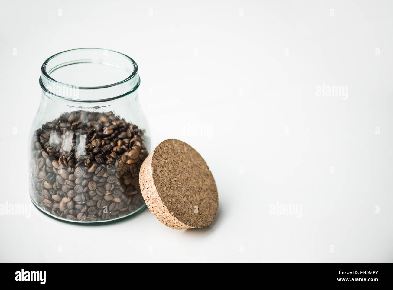 Bottiglia di vetro con i chicchi di caffè e sughero isolato su bianco Foto Stock