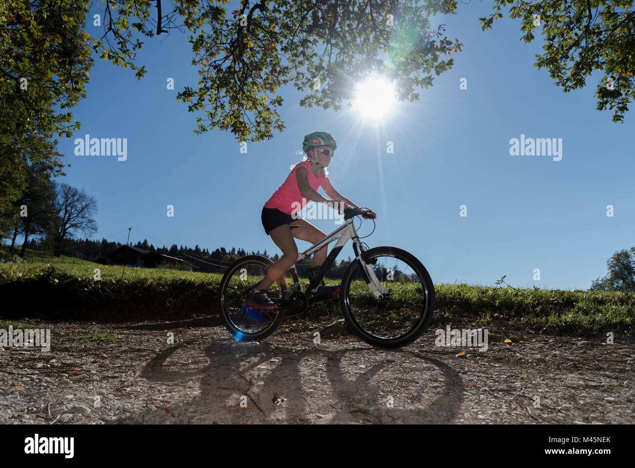 Ragazza mountain biker ciclismo giù nel sole sporco della pista Foto Stock