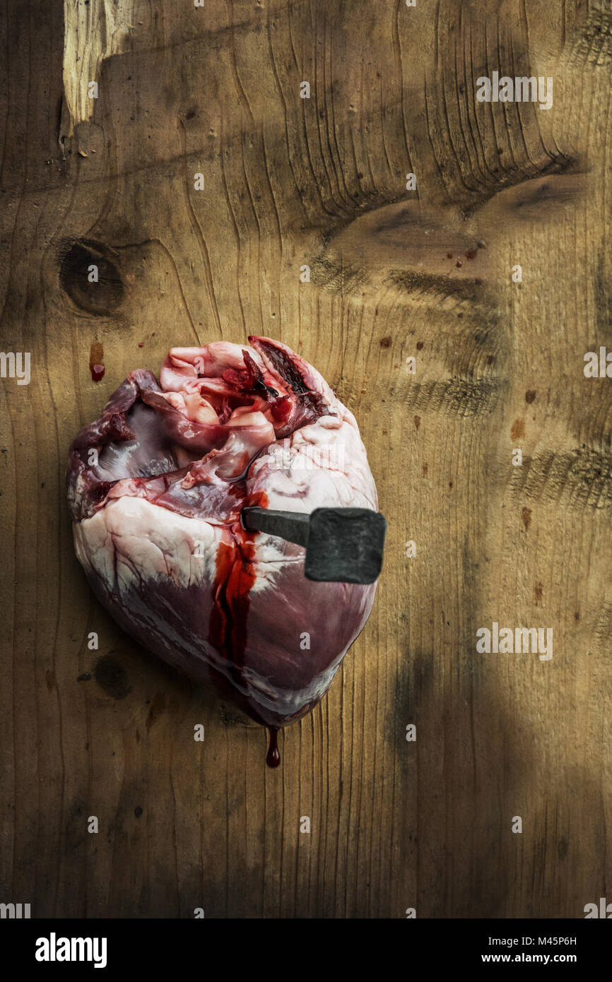 Un cuore inchiodato al legno con un enorme chiodo Foto Stock