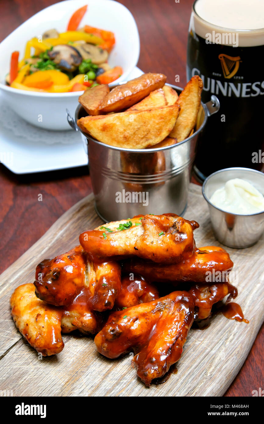 Ali di pollo si lancia in un barbecue e salsa al peperoncino dolce servito con il formaggio blu dip, chip e una pinta di Guinness, Doheny & Nesbitt Pub di Dublino, Irlanda Foto Stock