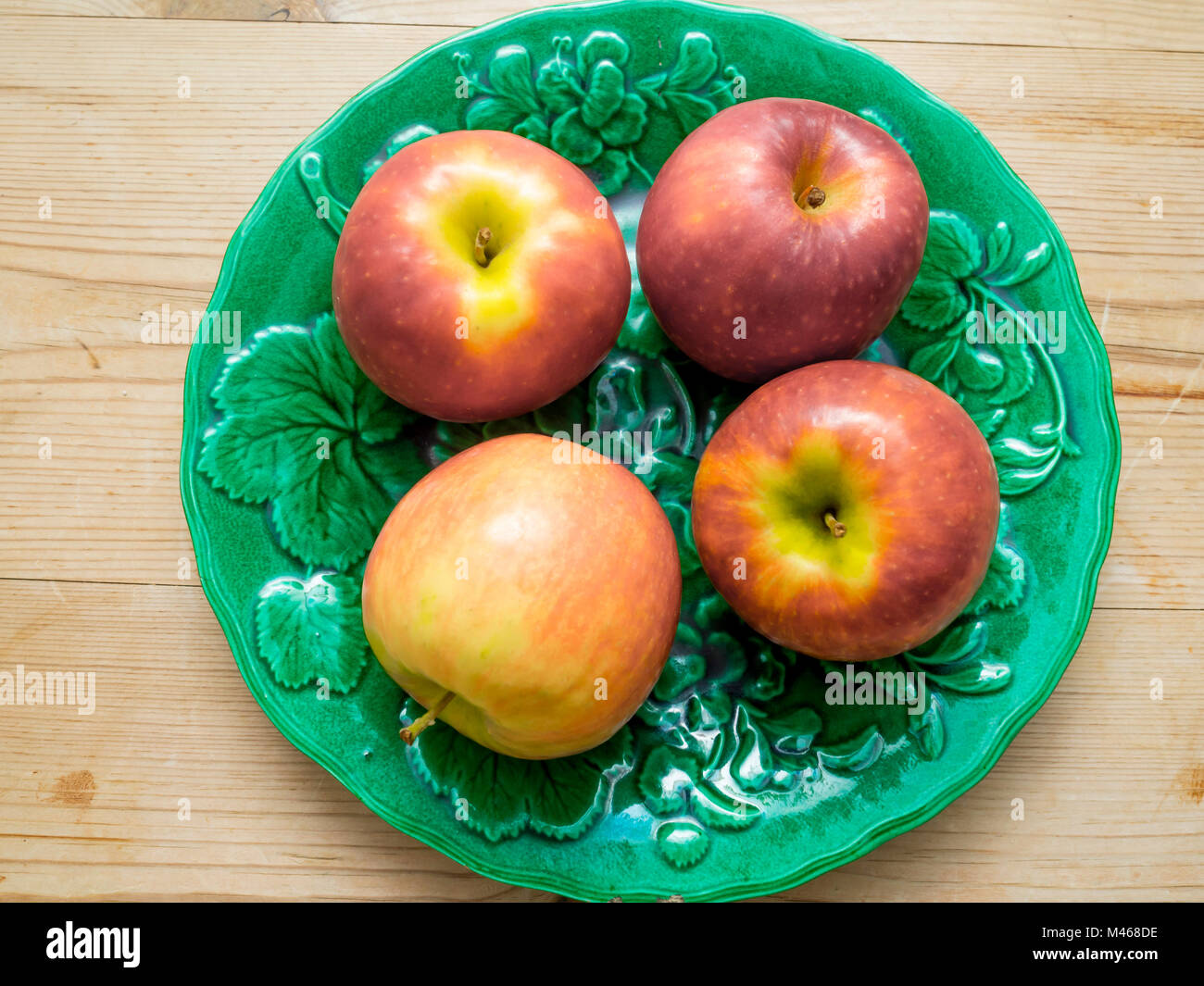Quattro coloratissimi Pink Lady mangiare le mele varietà Cripps Pink su una piastra verde Foto Stock