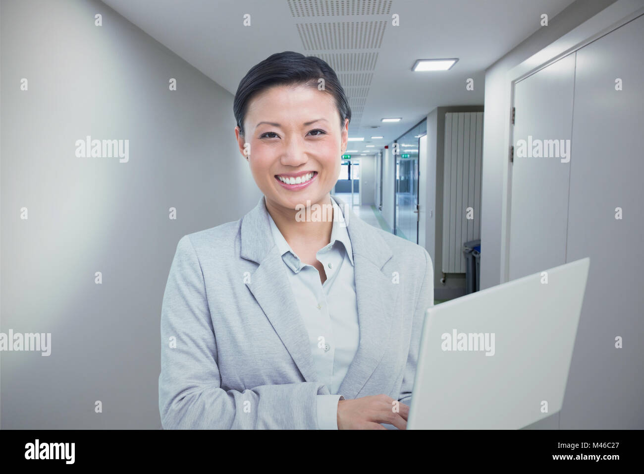 Immagine composita di imprenditrice utilizzando computer portatile con i colleghi dietro Foto Stock