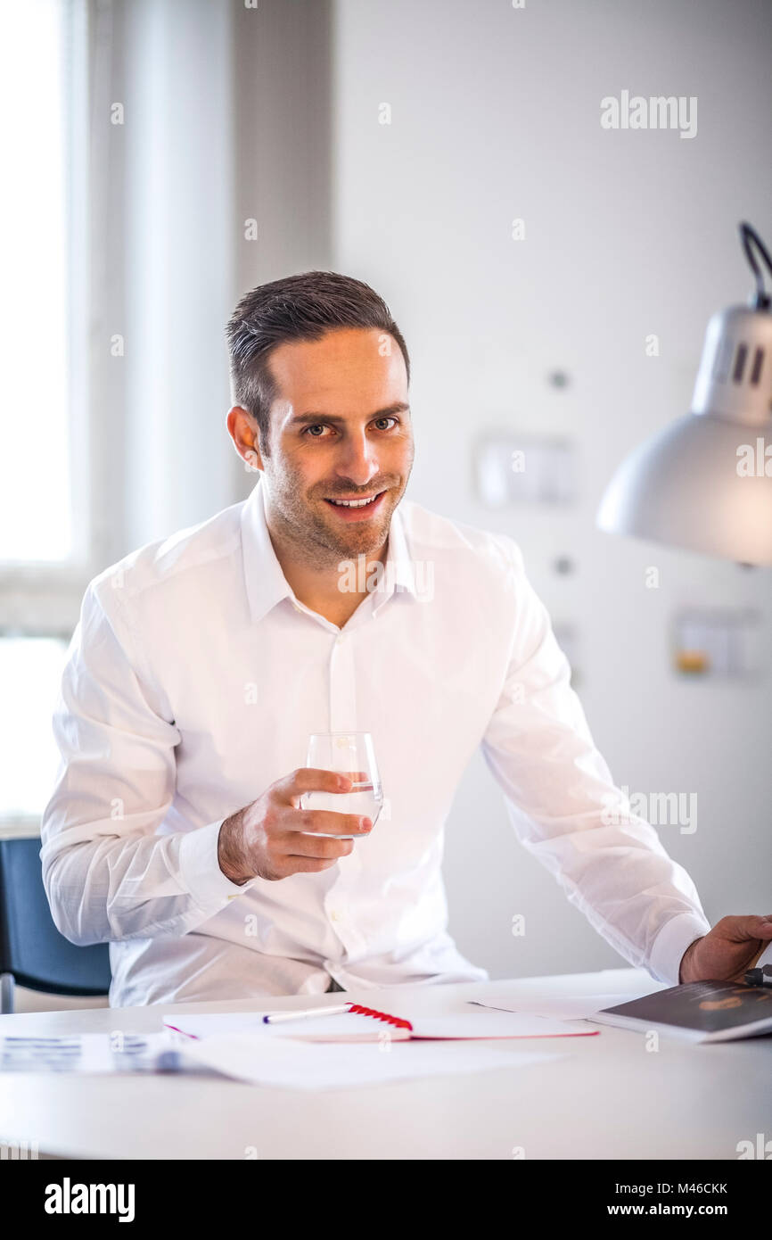 Ritratto di certi businessman holding bicchiere alla scrivania in ufficio Foto Stock