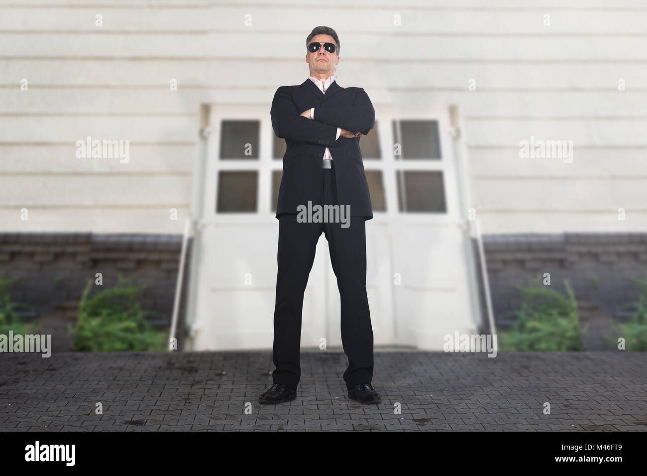 Ritratto di un serio maschio guardia di sicurezza permanente al entrata dell'edificio Foto Stock