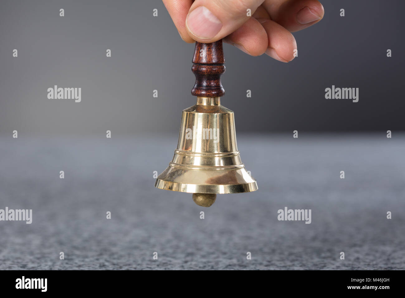 Close-up di una persona mano che tiene un campanello Foto Stock