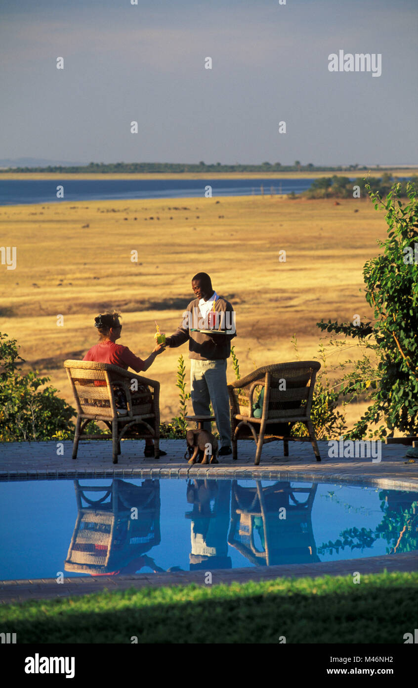 Lo Zimbabwe. Il lago Kariba. Katete Safari Lodge. Tourist, donna. Cameriere che serve drink. Foto Stock